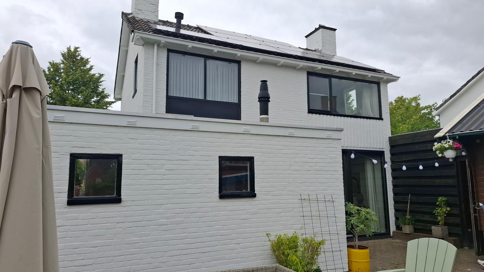 Wit geschilderde gevel van een woning met zwarte kozijnen — buitenschilderwerk in Groningen