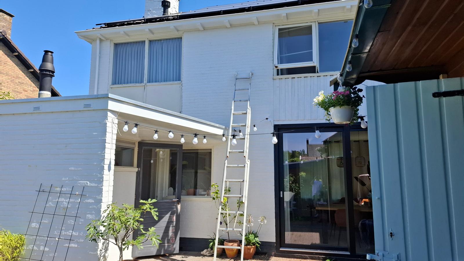 Schilderwerk aan een witte gevel met ladder — Adeptschilder Groningen aan het werk